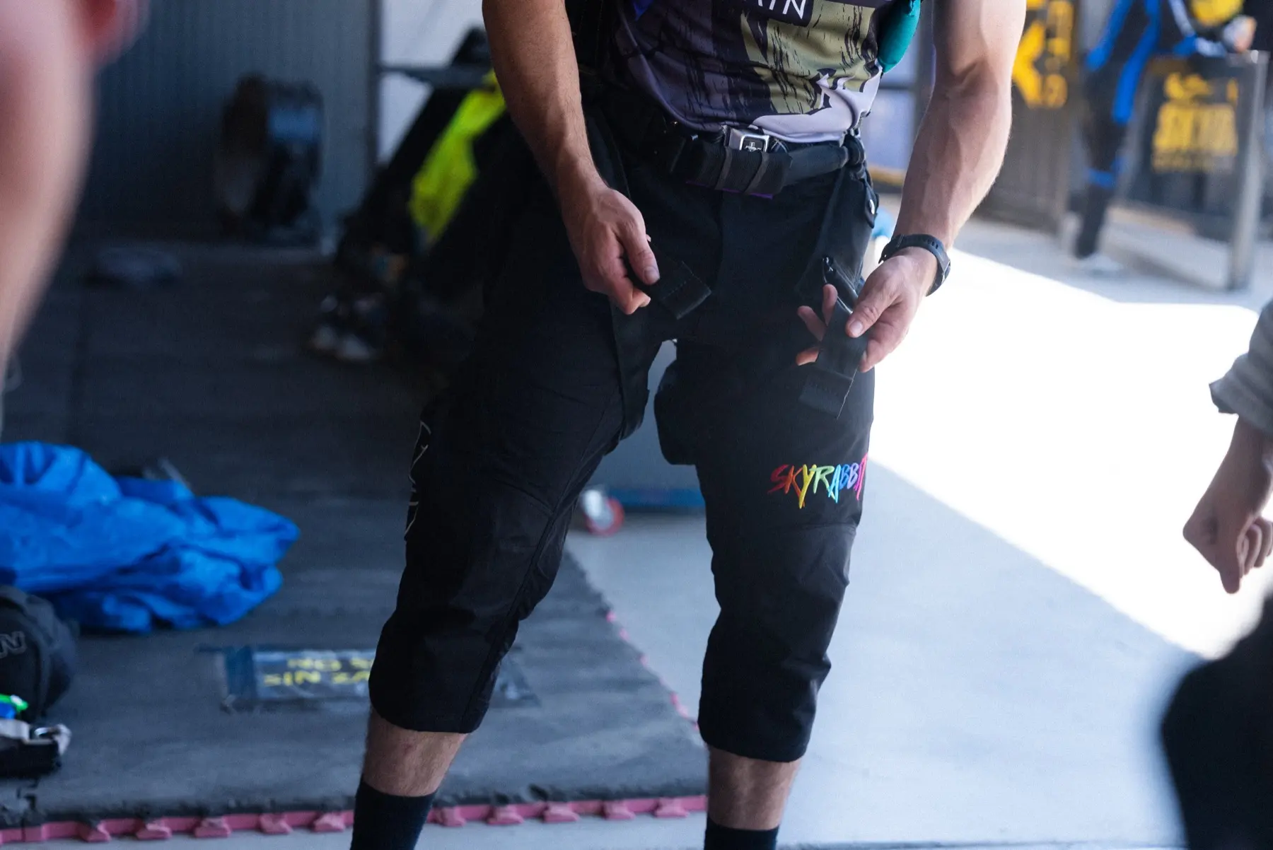 Standing male skydiver wearing Skyrabbit Swooper Pants with reinforced knees and utility pockets visible
